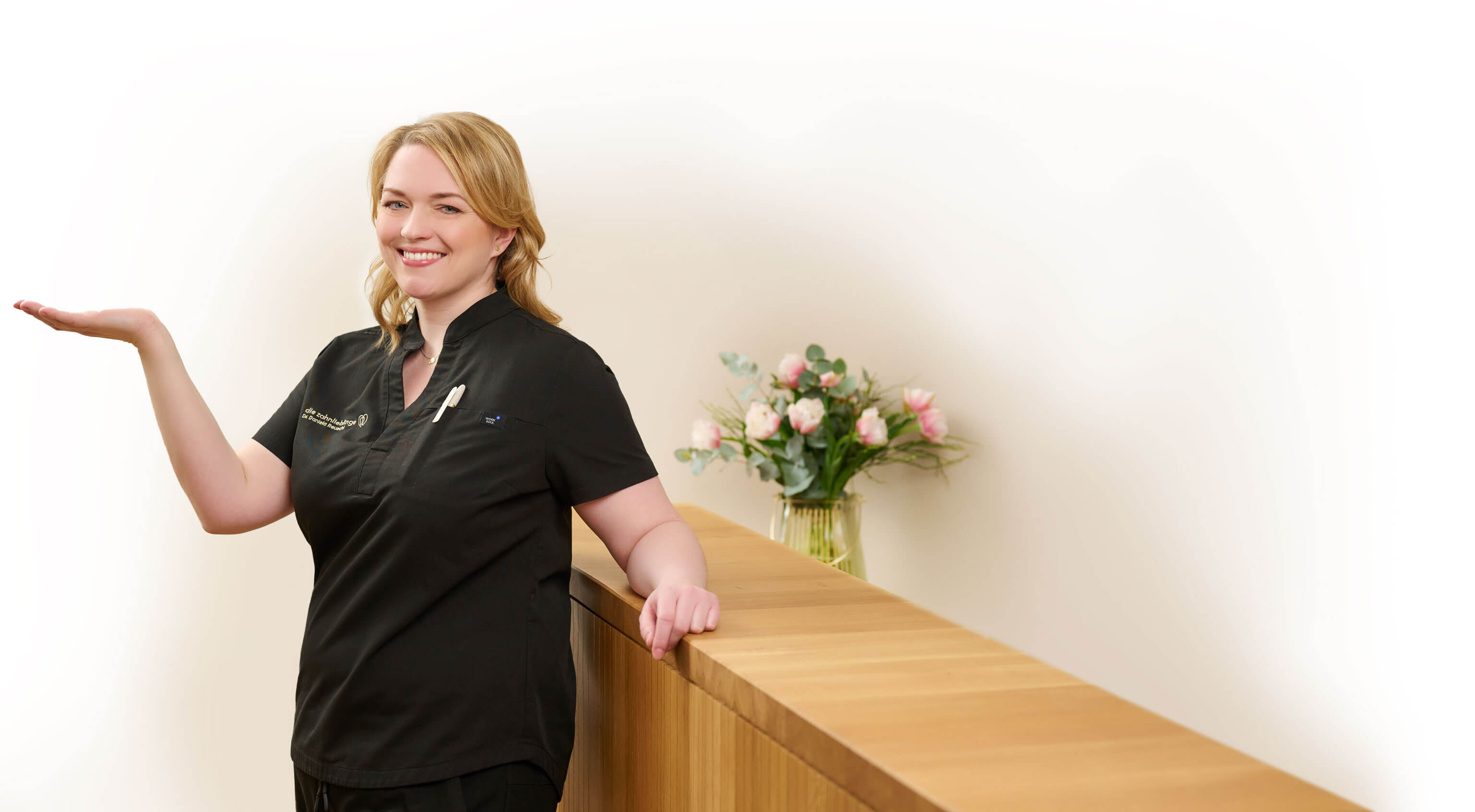 Zahnärztin Dr. Daniela Reuschl präsentiert das Logo ihrer Zahnarztpraxis Zahnlieblinge, das die Form eines Herzes mit der Form eines Zahns vereinrt